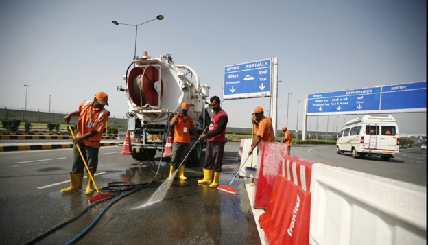 Sanitation workers cleaning a road using water jetting equipment